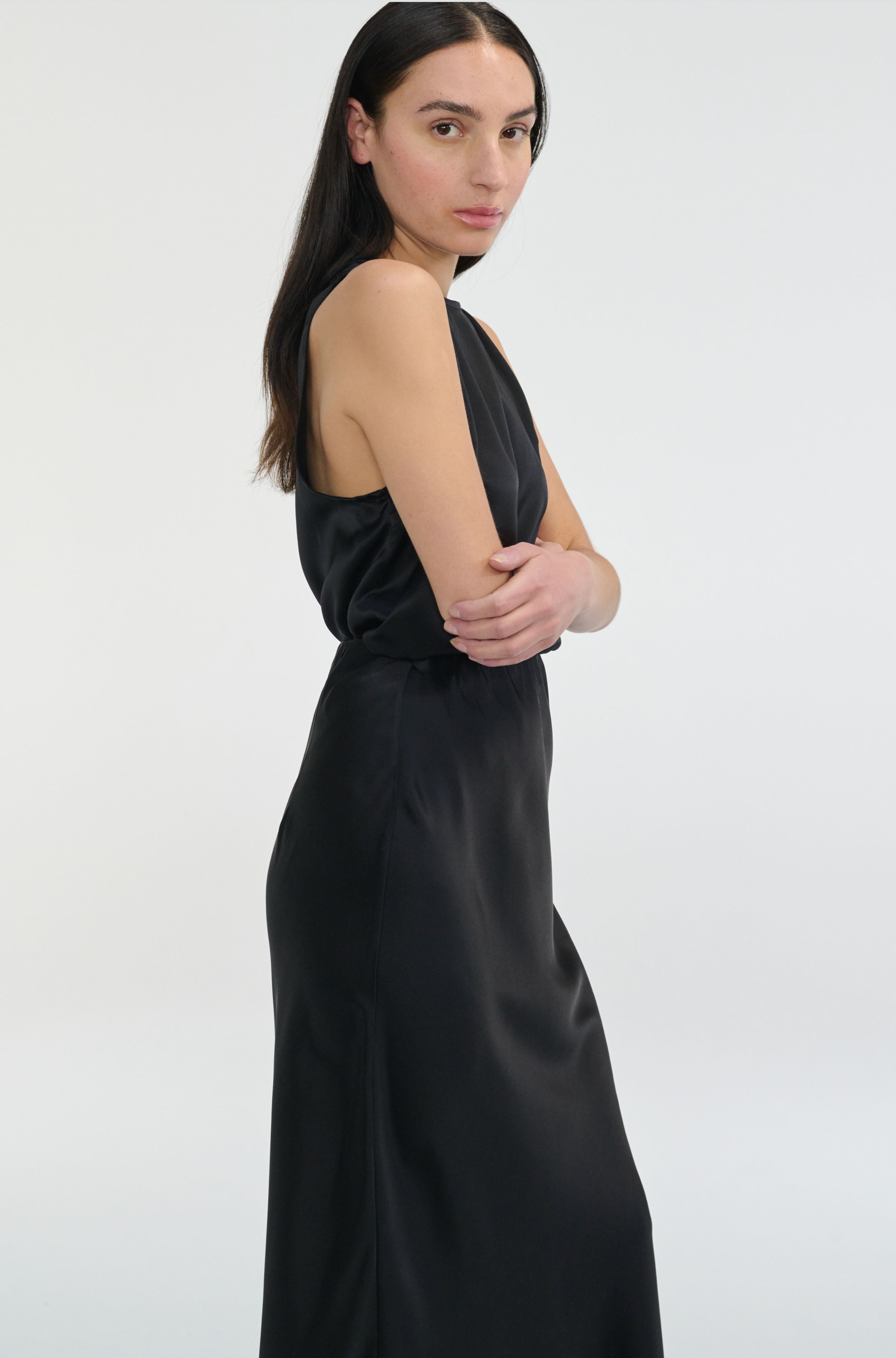 Woman wearing a black silk top and skirt set on a white background