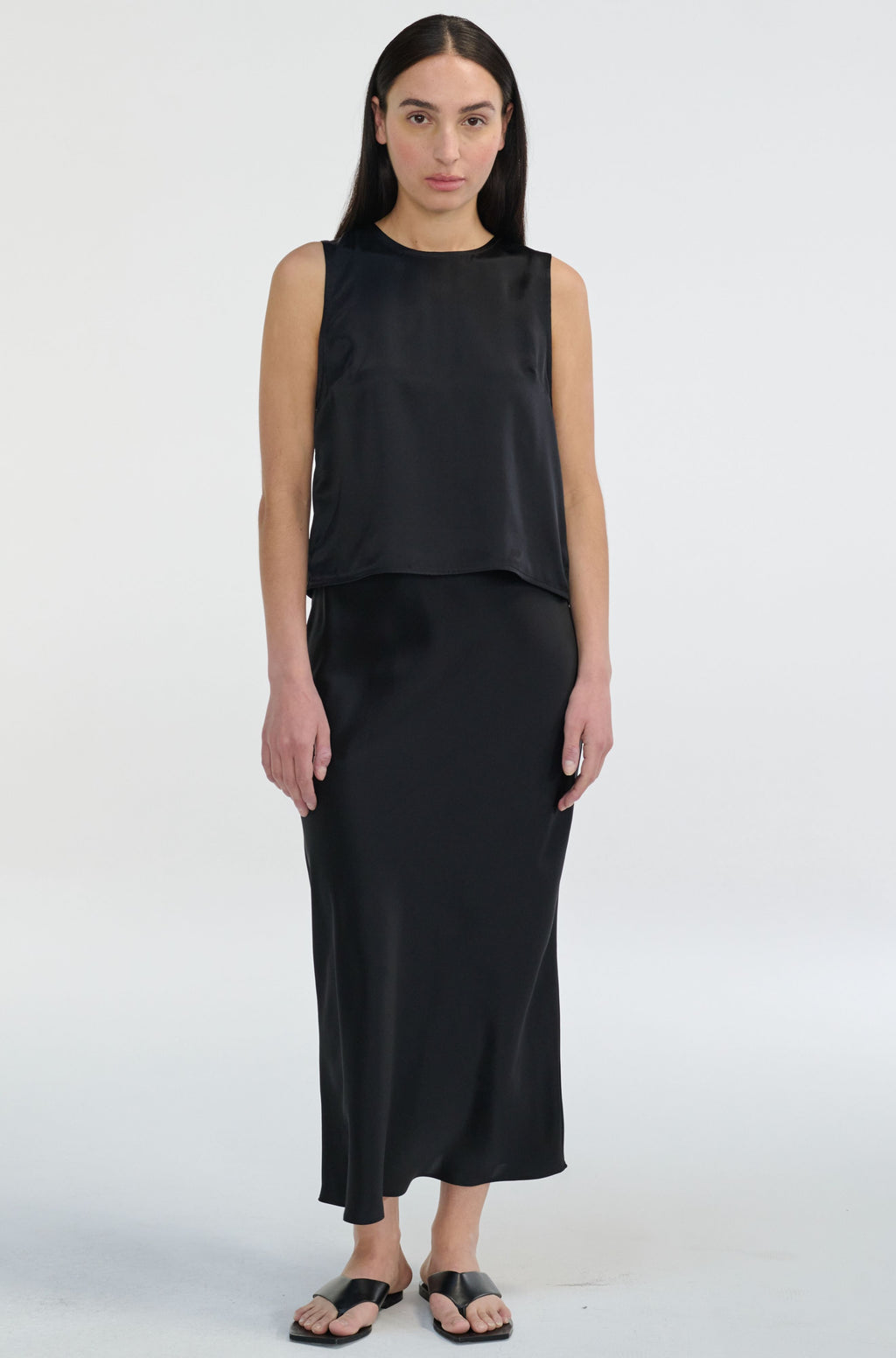 Woman wearing a black sleeveless top and skirt set on a white background