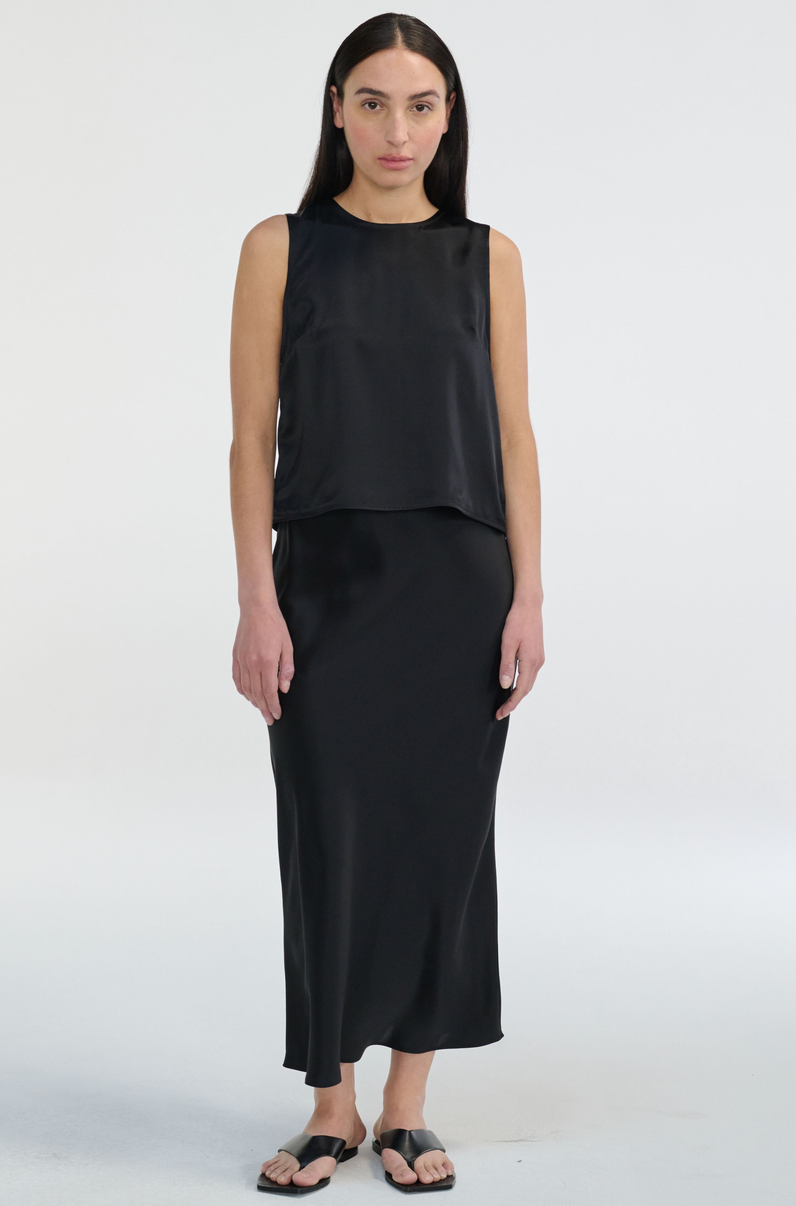 Woman wearing a black sleeveless top and skirt set on a white background