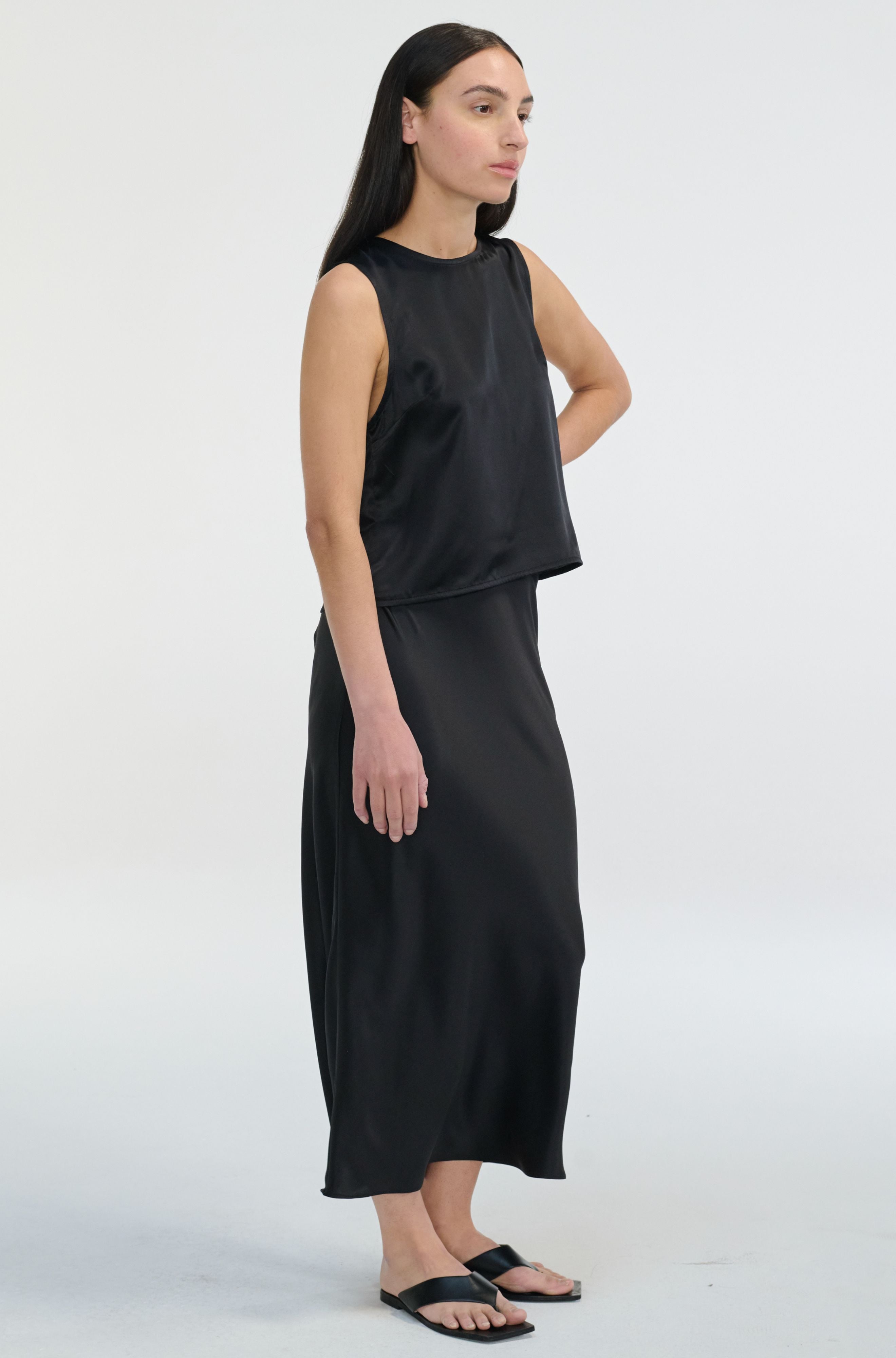 Woman wearing a black sleeveless top and black skirt on a white background