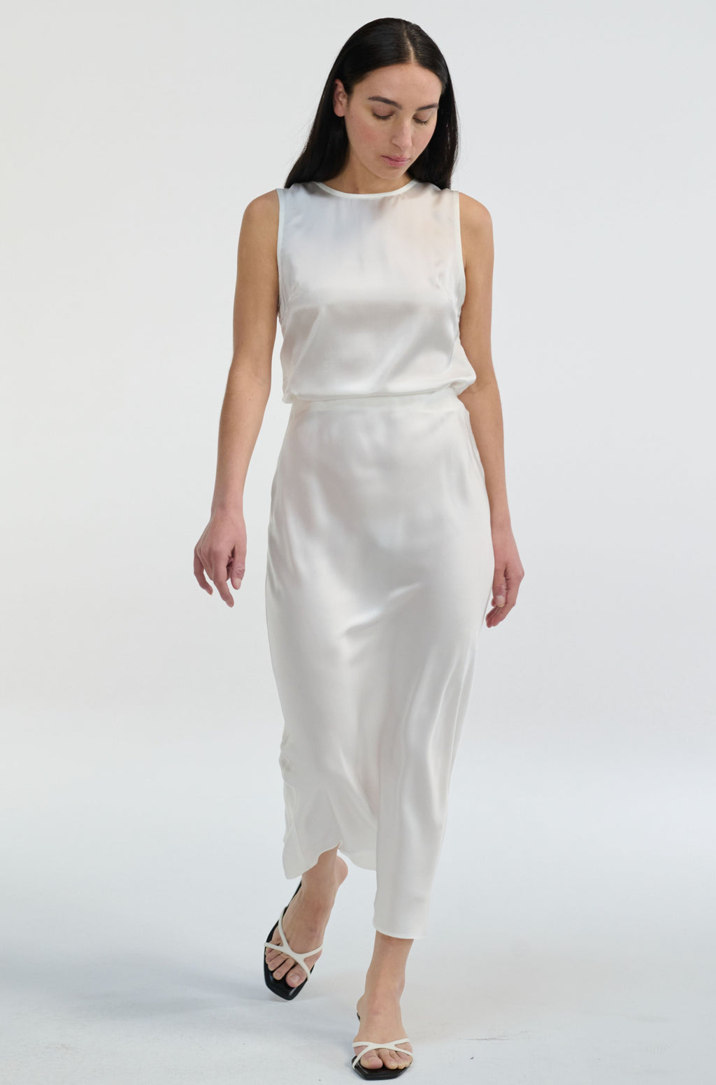 Woman wearing a white silk top and skit set on a white background