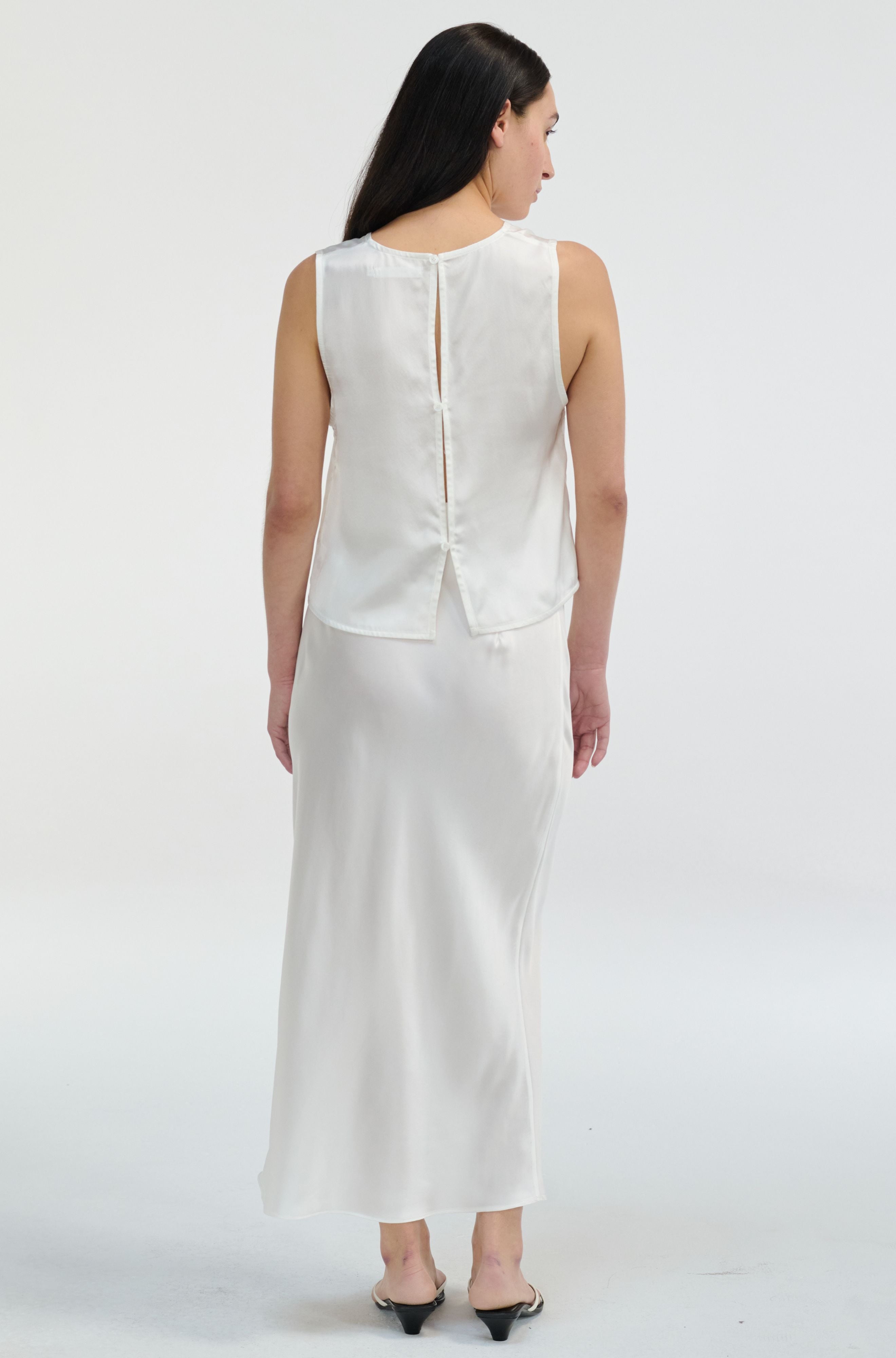 Woman wearing a white sleeveless top and skirt set on a white background