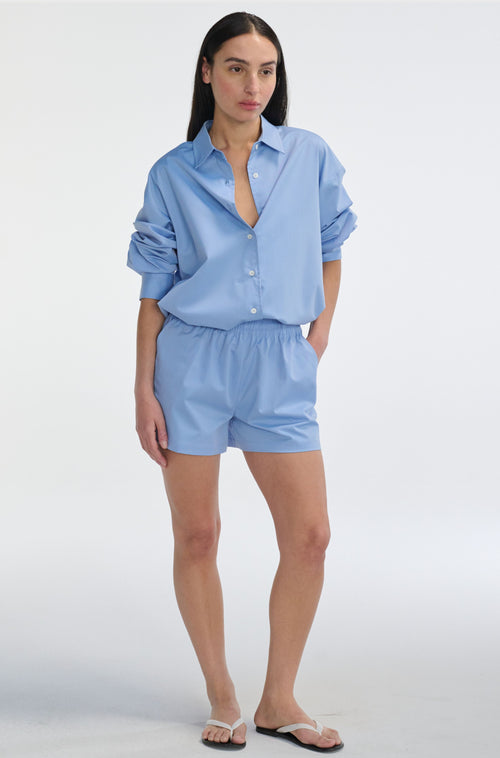 Woman wearing a light blue shirt and shorts set on a white background