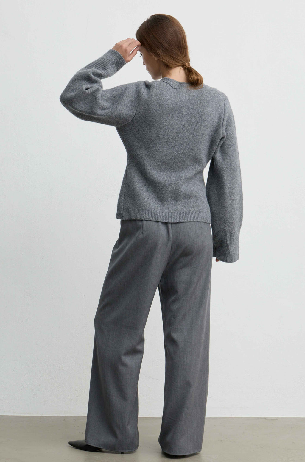 A woman shown from the back wearing a heather gray knit sweater and matching wide-leg trousers against a plain light gray studio background.