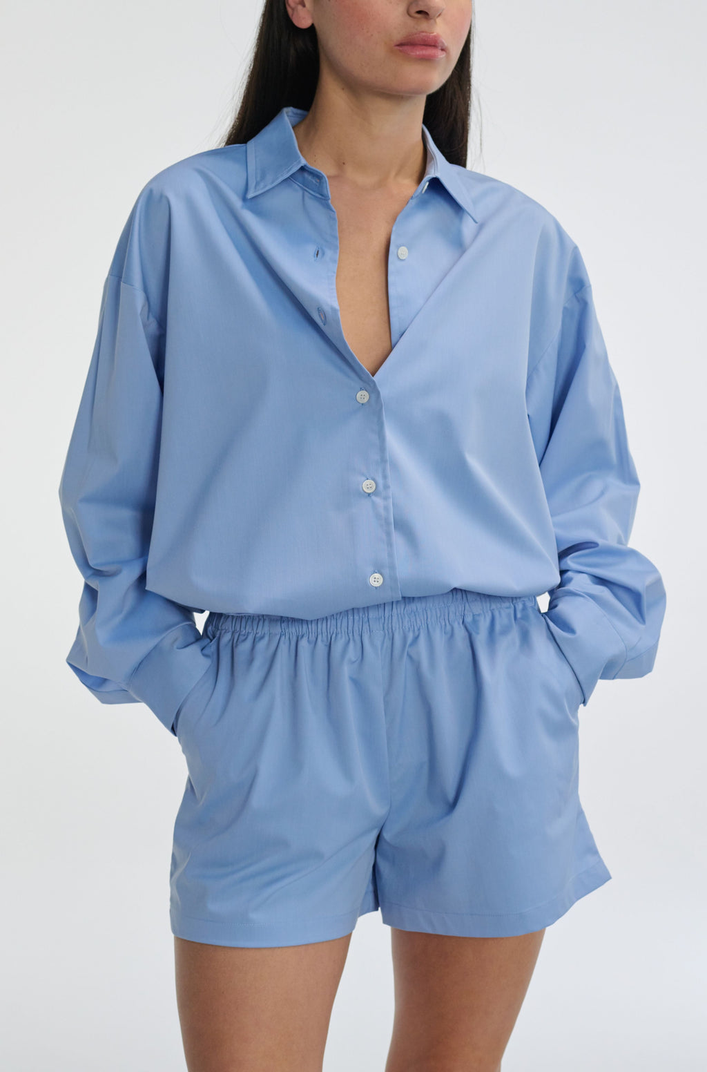 Woman wearing a light blue shirt and shorts set on a white background