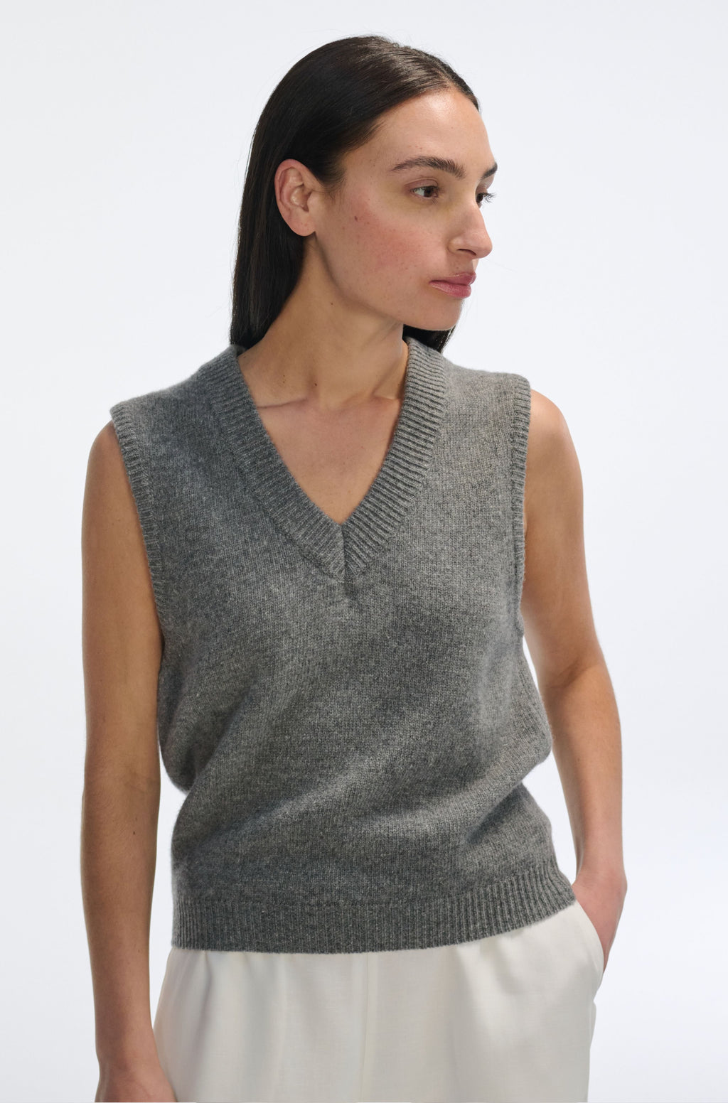 Woman wearing a gray sleeveless sweater on a white background