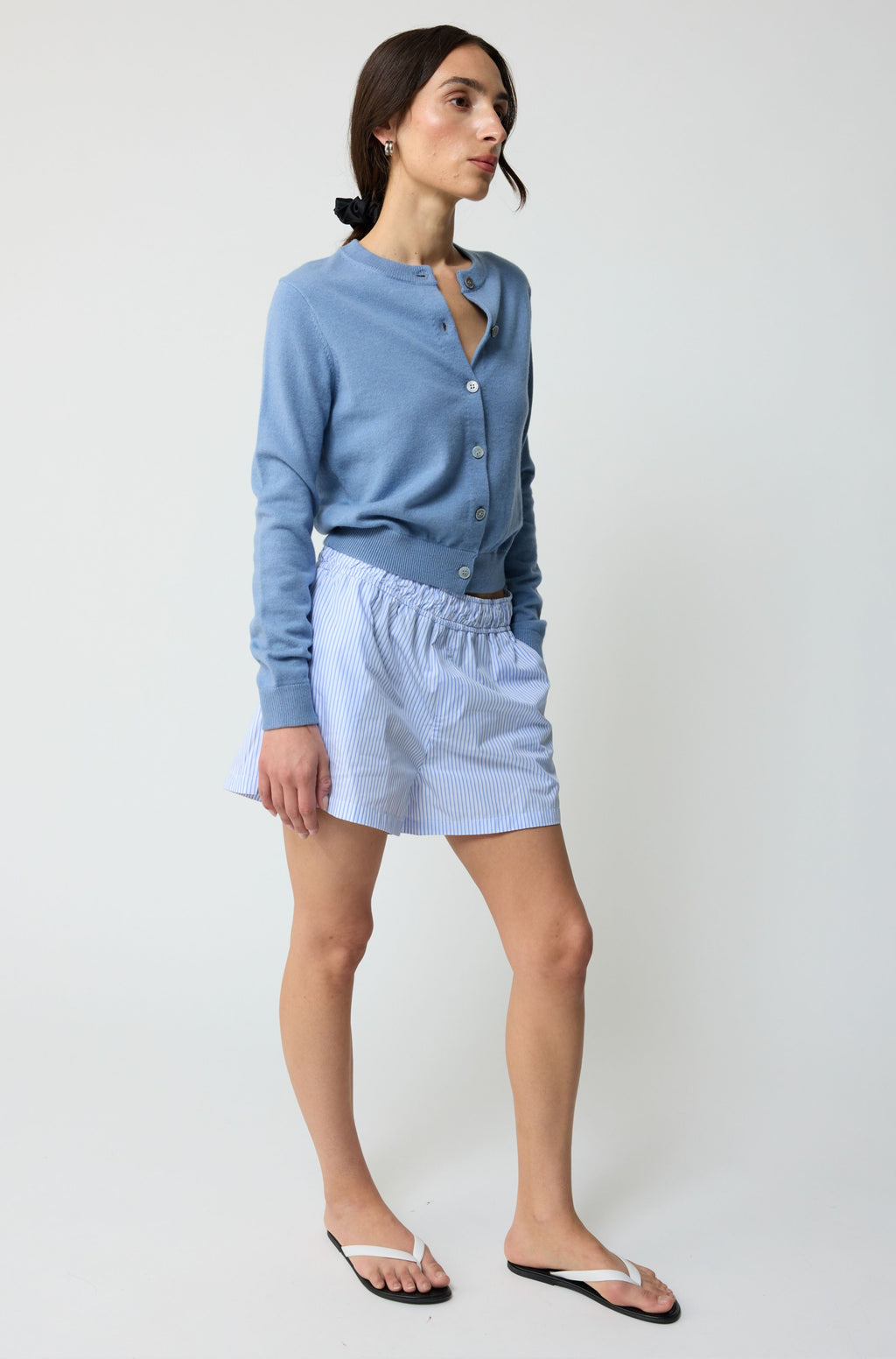 Woman wearing a light blue cardigan and skirt on a white background