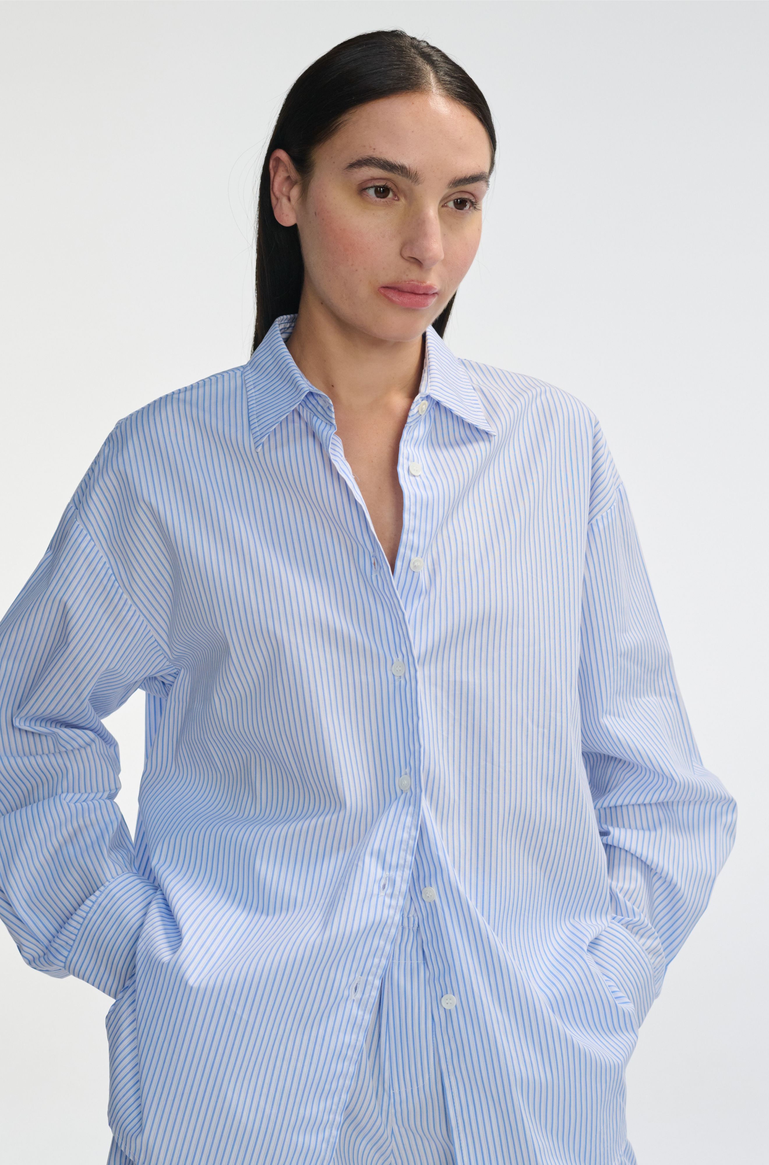 Woman wearing a light blue striped shirt against a white background