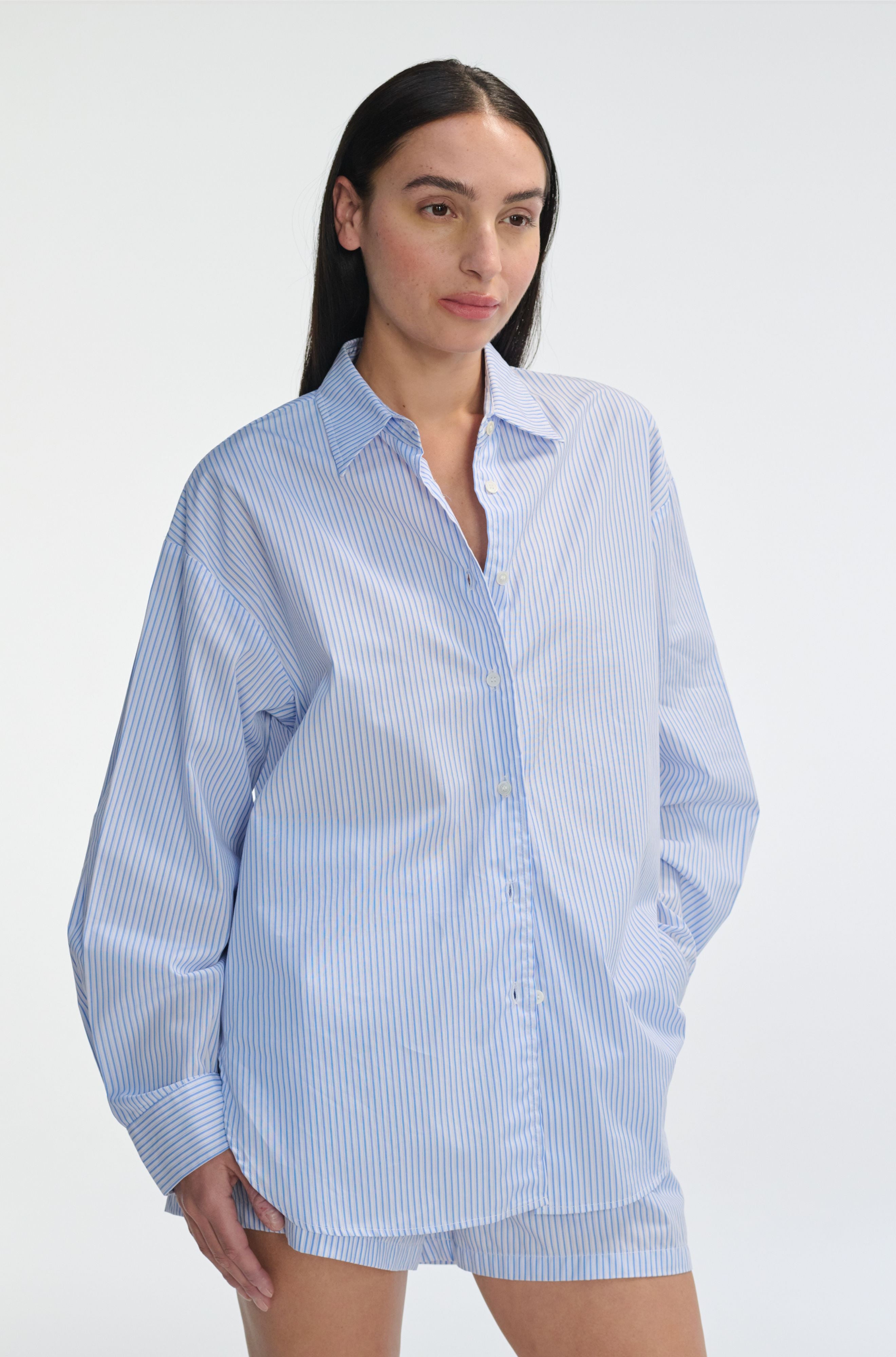 Woman wearing a light blue striped shirt against a white background