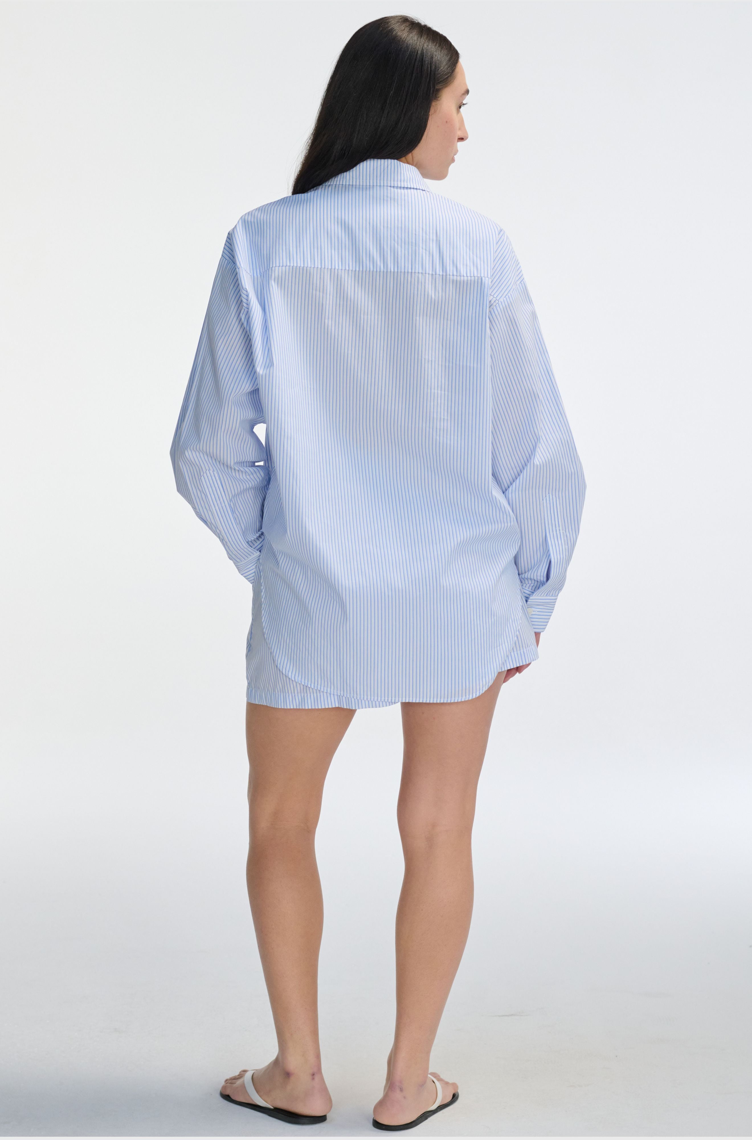 Person wearing a light blue checkered shirt on a white background