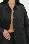 Person wearing a black button-up shirt with a plain background