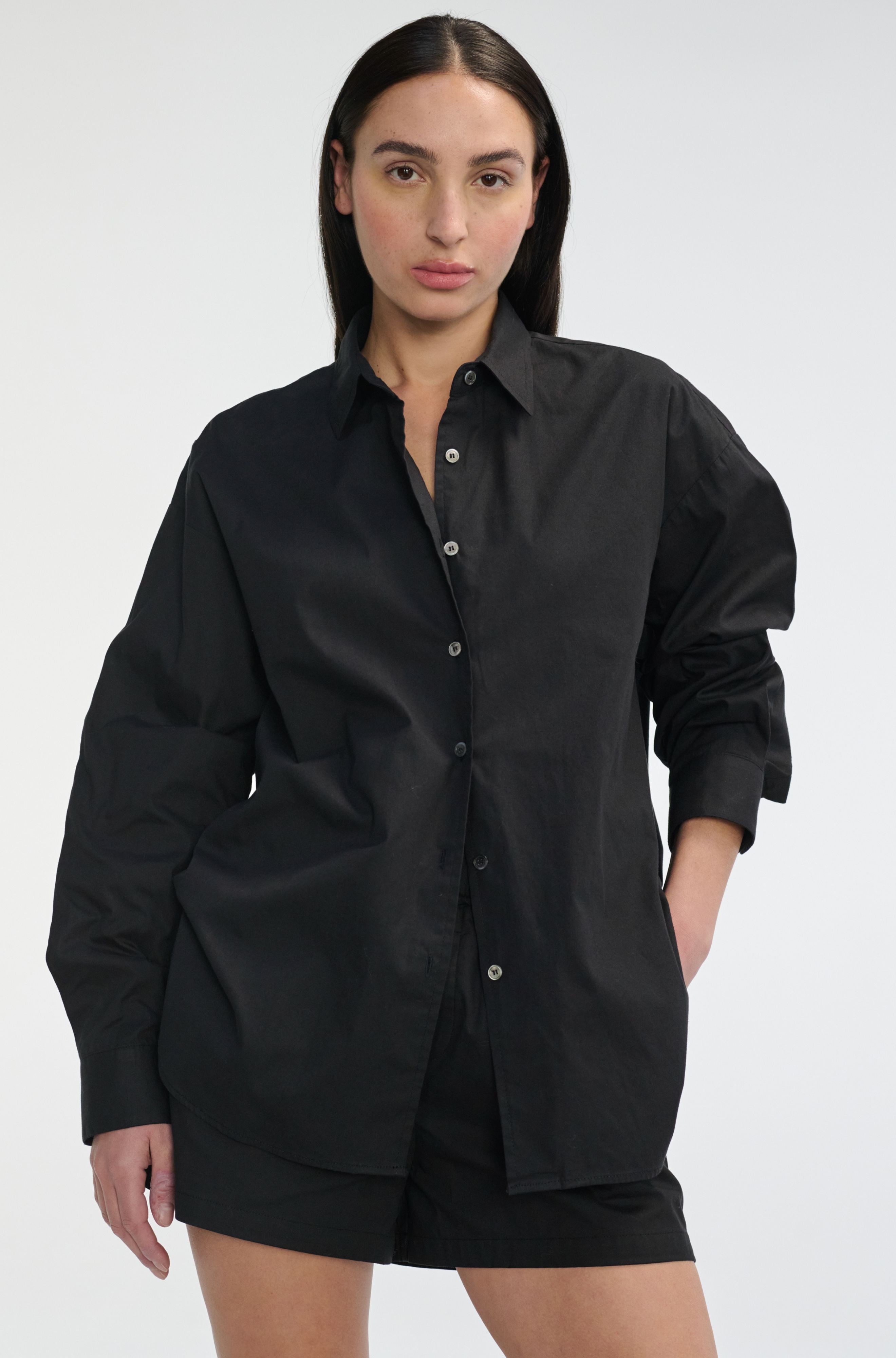 Woman wearing a black oversized shirt on a white background