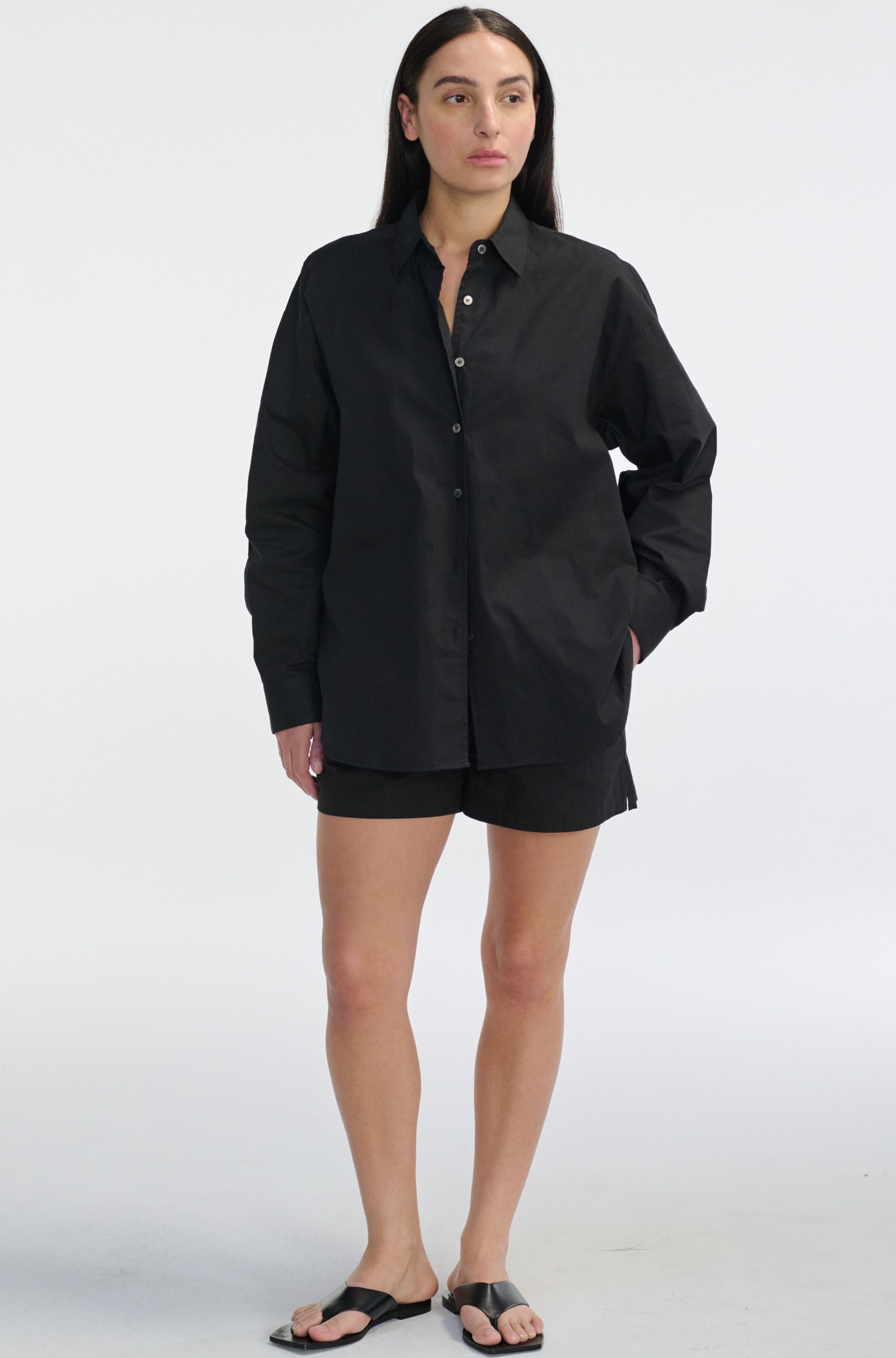 Person wearing a black shirt and shorts on a white background