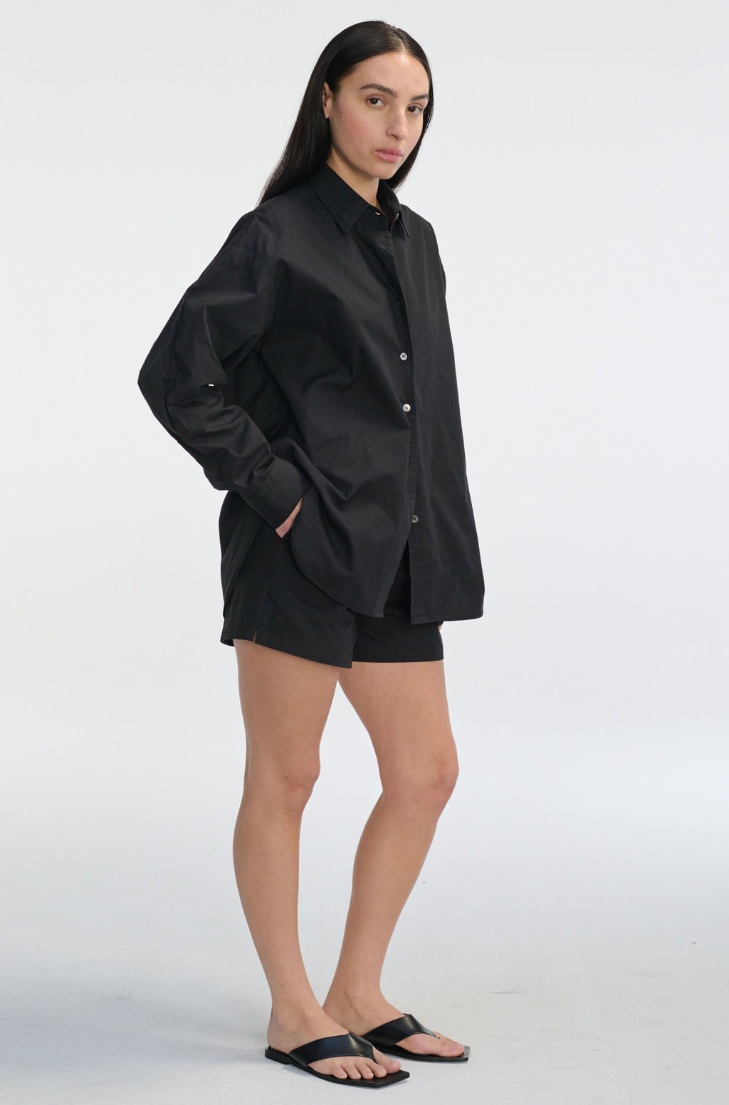 Person wearing a black oversized shirt and shorts on a white background