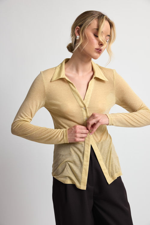 Woman wearing a beige long-sleeve shirt against a white background