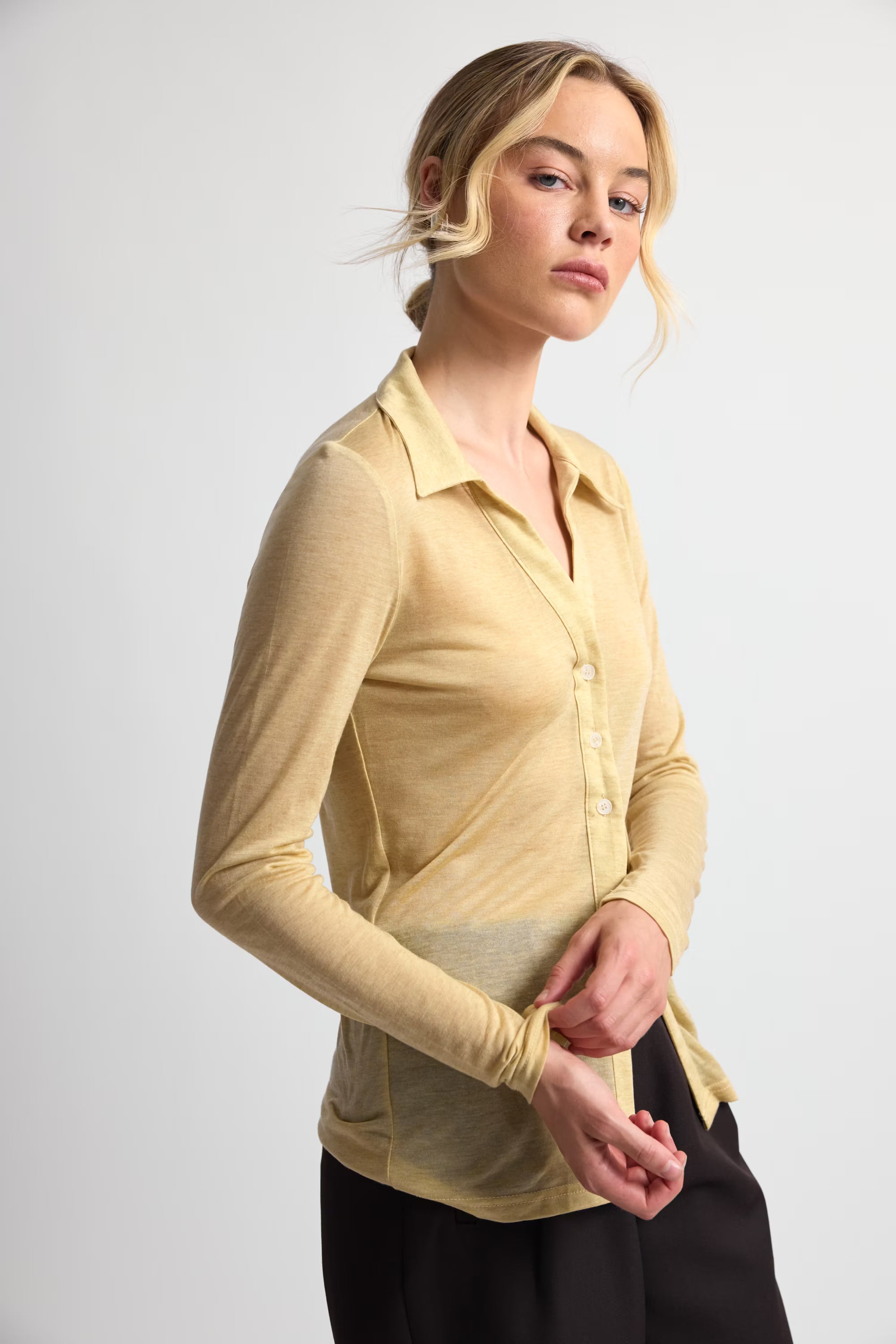 Woman wearing a yellow long-sleeve shirt against a white background