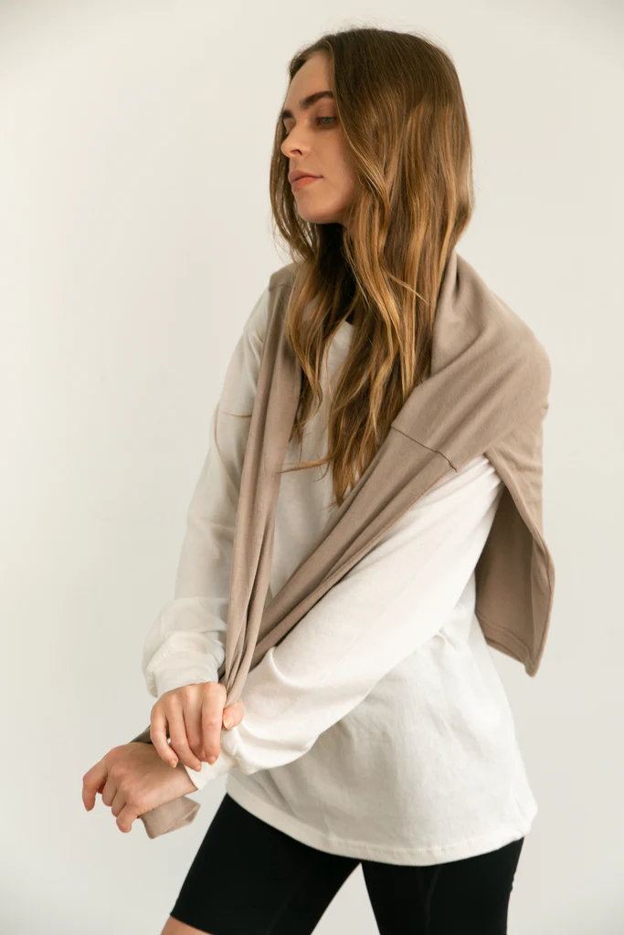 Woman wearing a beige long sleeve shirt over a long sleeve white shirt and black biker shorts