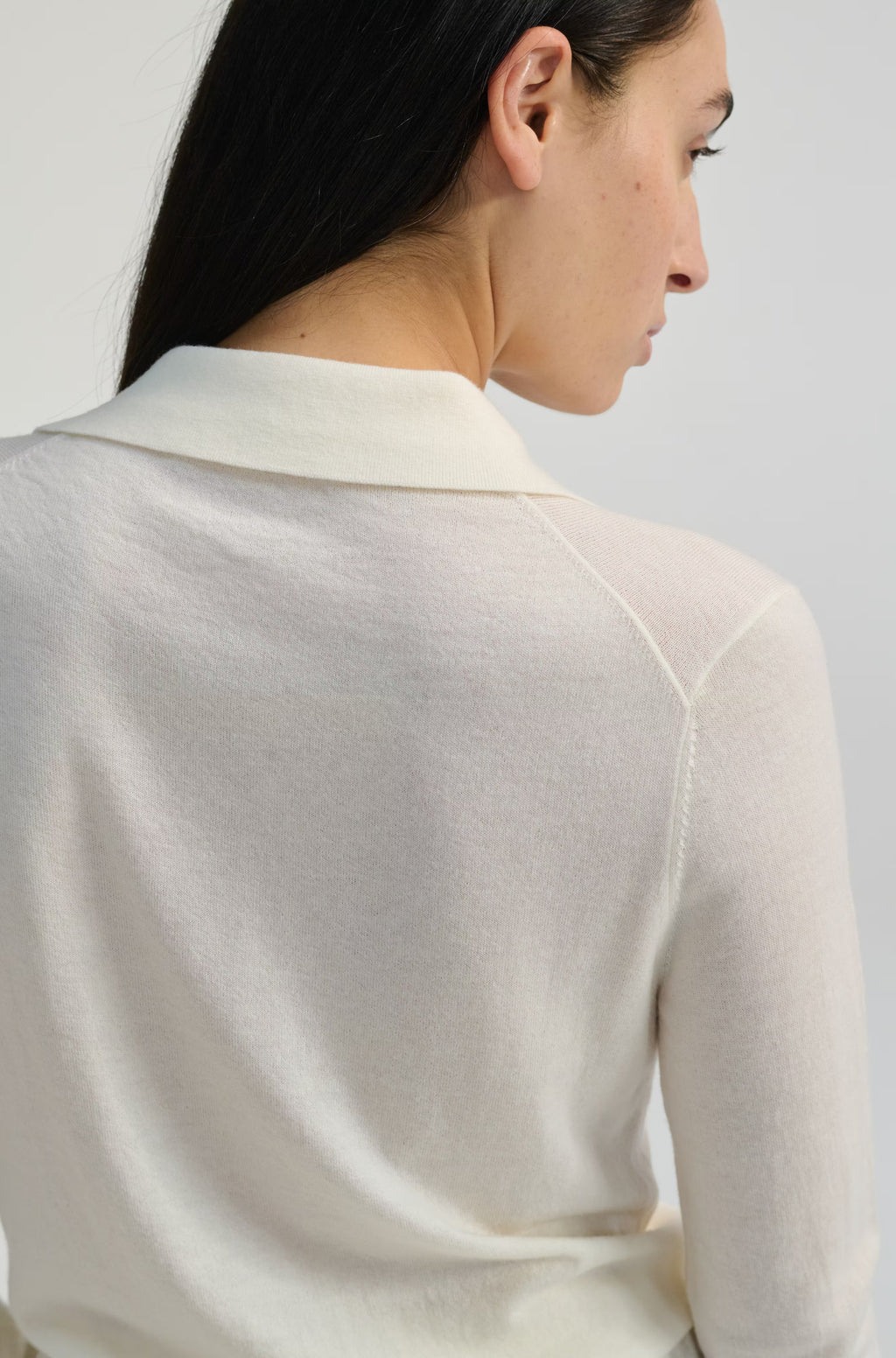 Woman wearing a light-colored sweater against a plain background