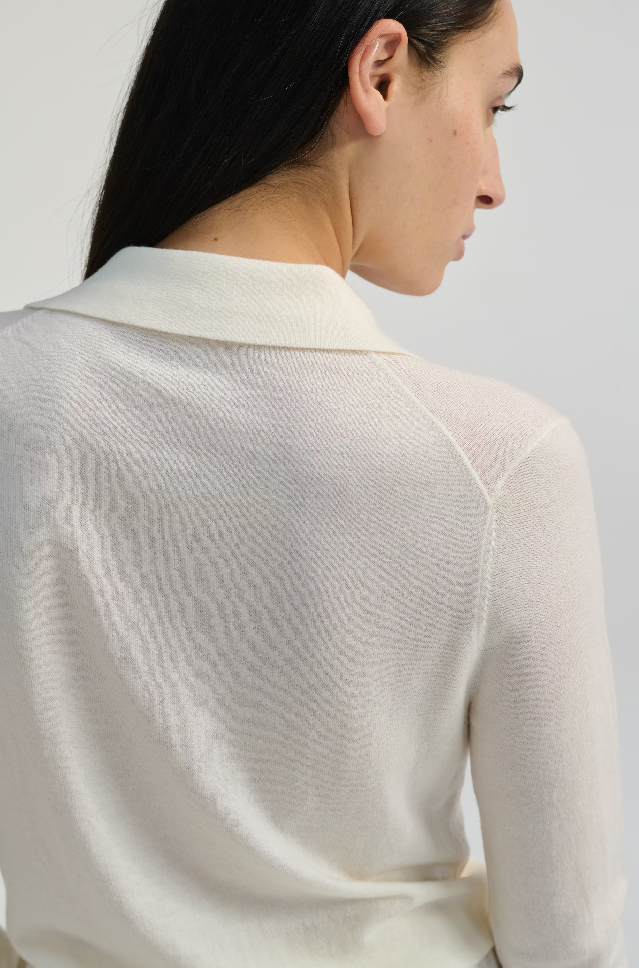 Woman wearing a light-colored sweater against a plain background