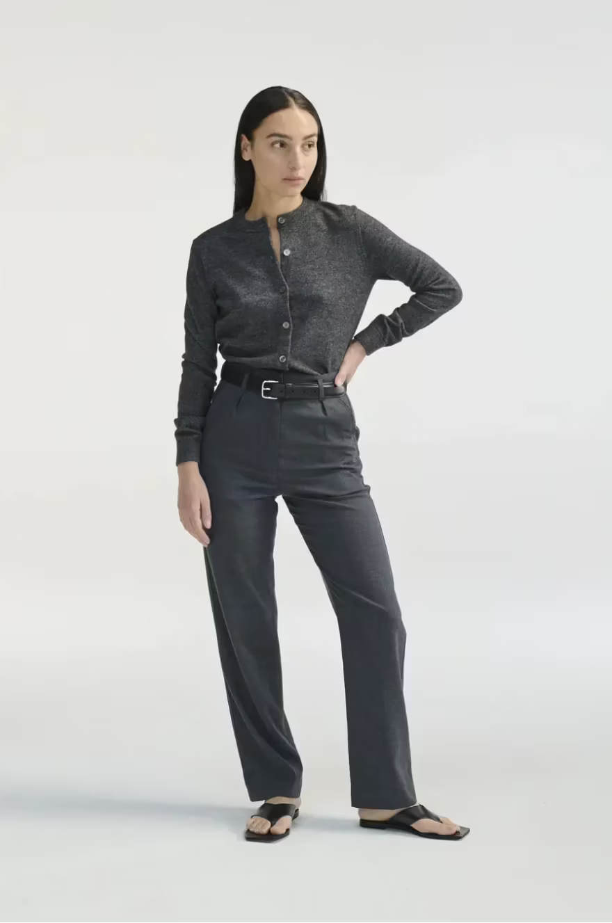 Woman wearing a dark gray button-up shirt and pants on a white background